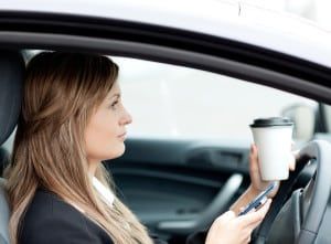 Blond businesswoman sending a text while driving