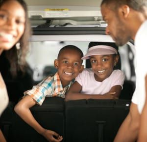 A happy family  with their minivan.