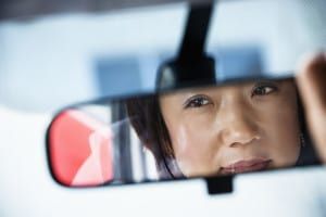 bigstock-Woman-Looking-in-Rearview-Mirr-7629395