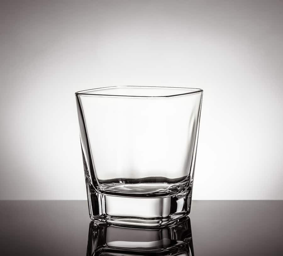 На столе пустой стакан. Пустой стакан для виски. Пустой стакан. Бокал пустой для виски. Стакан с виски на белом фоне.